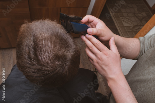 A man holds a hair clipper in his hand. The process of cutting hair close-up. Top view of the head
