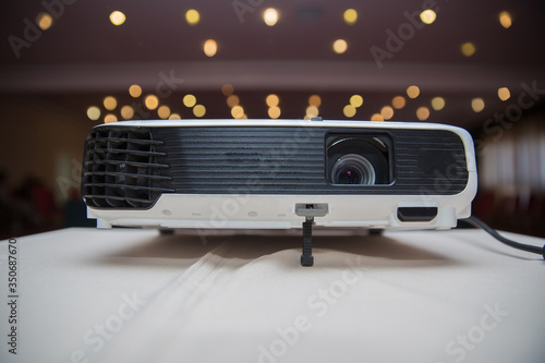 LCD Projector technology video presentation and home Entertainment object . mini led projector on wood table in a room projector home theater idea and concept . Close up projector in conference room .