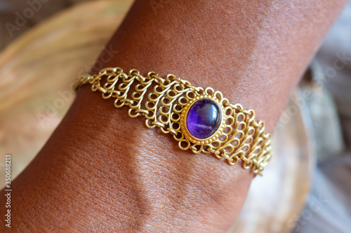 Hand wearing elegant brass wire amethyst mineral stone bead bracelet on the wrist