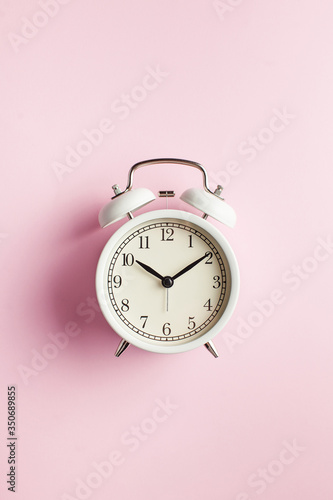 Flatlay white alarm clock on a pink, copy space. Concept for time planning. Minimalism, of time is running.