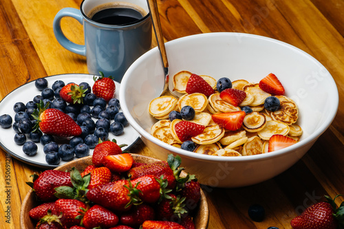 Tiny pancakes for breakfast. Pancakes with strawberries and blueberries cooked in the morning for breakfast in the home kitchen. Food Background.