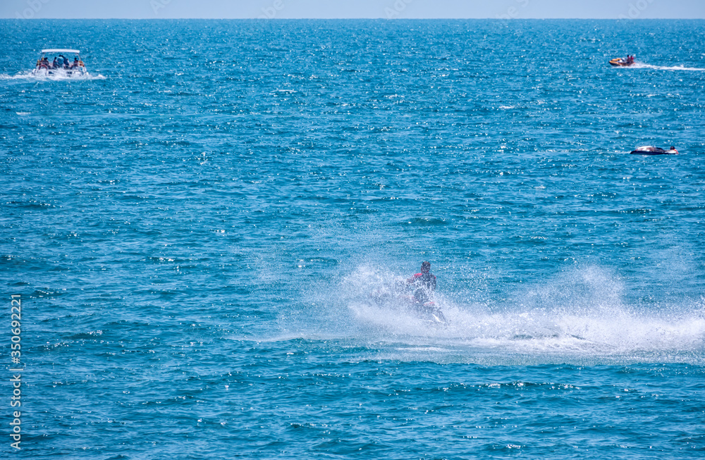 The jet ski swims quickly across the sea, picking up many waves and splashes.