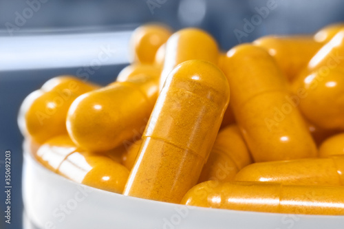 Orange capsules with Curcumin powder indian spice, macro photography. Turmeric benefits and nutrition, supplements and microelements, health care and immune system concept photo