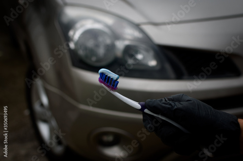 Technician with holding toothbrush and toothpaste to shine and brighten the headlights of the car. Topical car wash and care. car care. headlight polishing and care concept.
