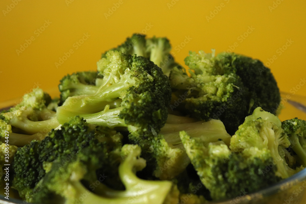 green boiled broccoli on the yellow background, close up shot