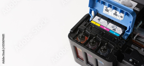 Up close, ink tanks from a printer displaying CMYK Cyan, Magenta, Yellow and Key colors, continuous refill system. Computer and peripheral topic. print and color concept. copy space