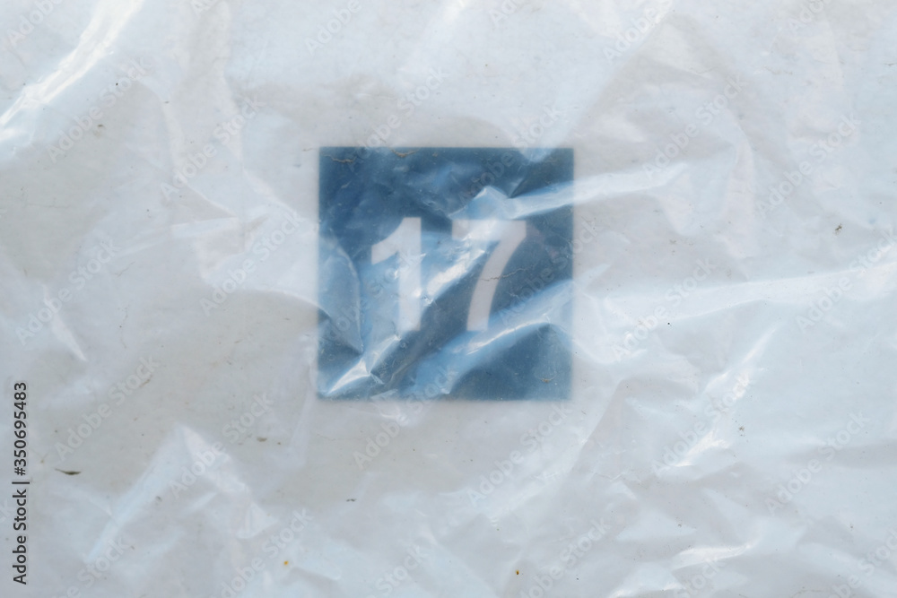 Obraz premium Number Seventeen on stadium seat under the plastic bag. Numbers tell the seats of those who came to watch sports. Empty white plastic seats in a stadium. Matches to be played without fans.