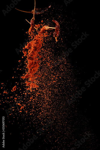 Fototapeta Naklejka Na Ścianę i Meble -  Red paprika spices powder explosion, flying chili pepper isolated on black background. Splash of spice background.