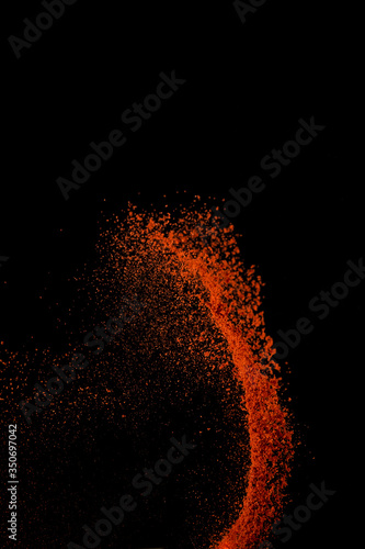 Fototapeta Naklejka Na Ścianę i Meble -  Red paprika spices powder explosion, flying chili pepper isolated on black background. Splash of spice background.