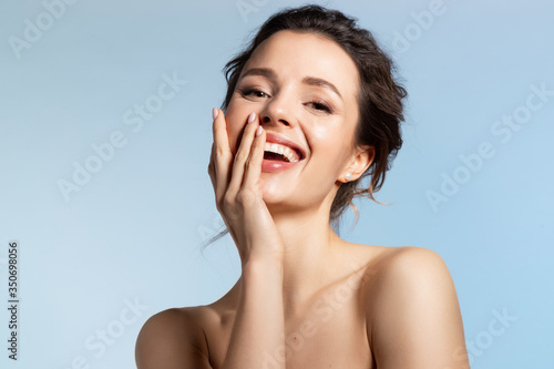 Beautiful model covering joyfully smiling open mouth with hand. Positive playful mood