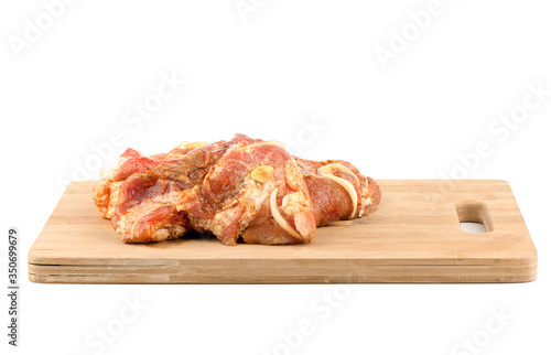 Pickled pork with onions and garlic on a wooden cutting board.