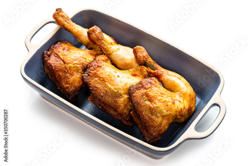 Baked chicken legs with vegetables in a ceramic baking dish. Isolate on a white background.