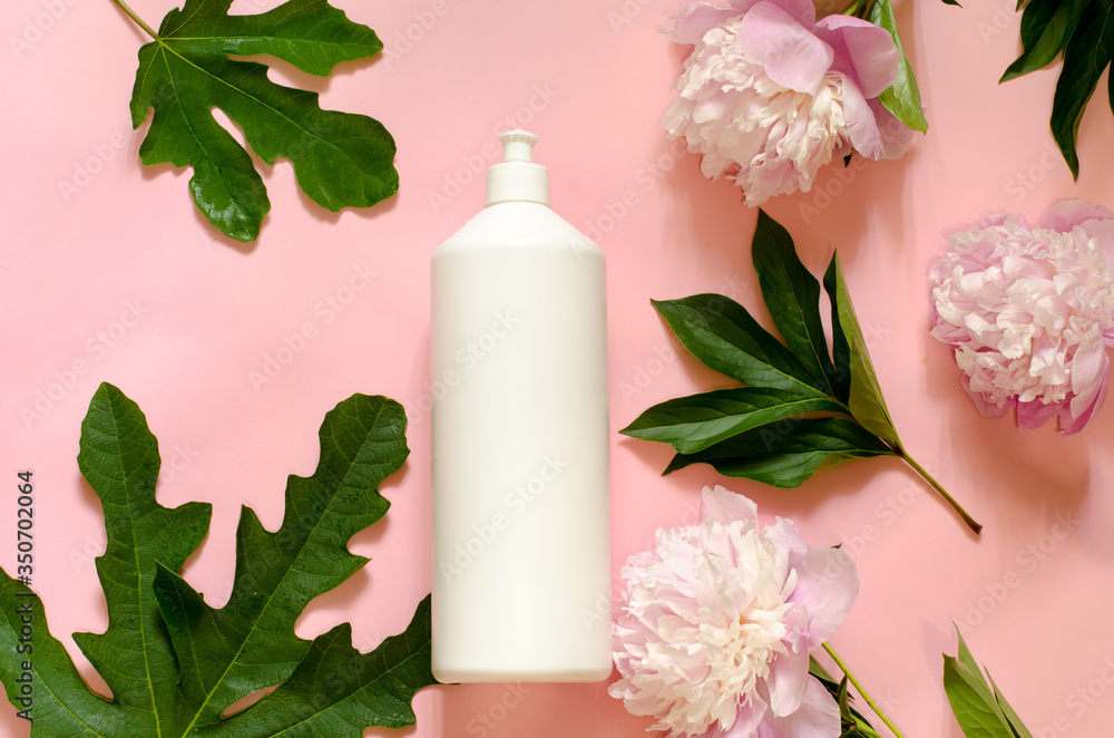 A large white plastic bottle with place for your text on a pink background with green leaves of plants. Beauty theme A large white plastic bottle with place for your text on a pink background with green leaves of plants. Beauty theme