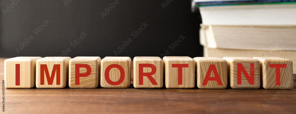 IMPORTANT word written on wooden cubes on the backround of stack of books. Education, medicine, business concept IMPORTANT word written on wooden cubes on the backround of stack of books. Education, medicine, business concept