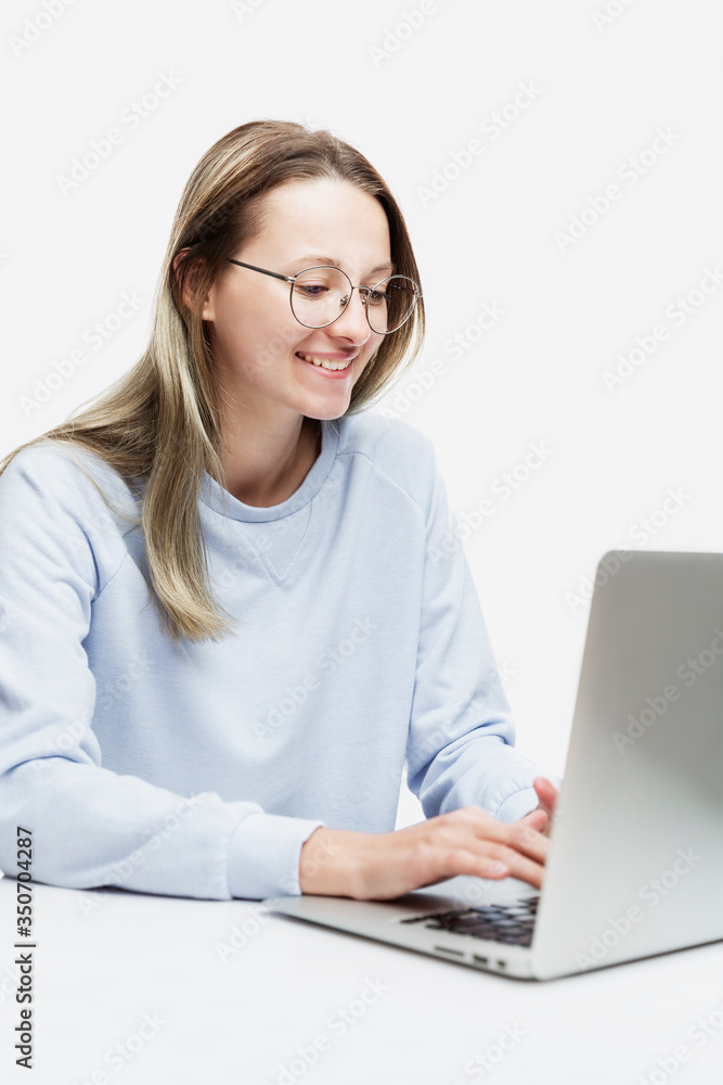 A smiling young girl in glasses stands with a laptop in her hands. Education, work and blogging. Isolated on a white background. Vertical. A smiling young girl in glasses stands with a laptop in her hands. Education, work and blogging. Isolated on a white background. Vertical.