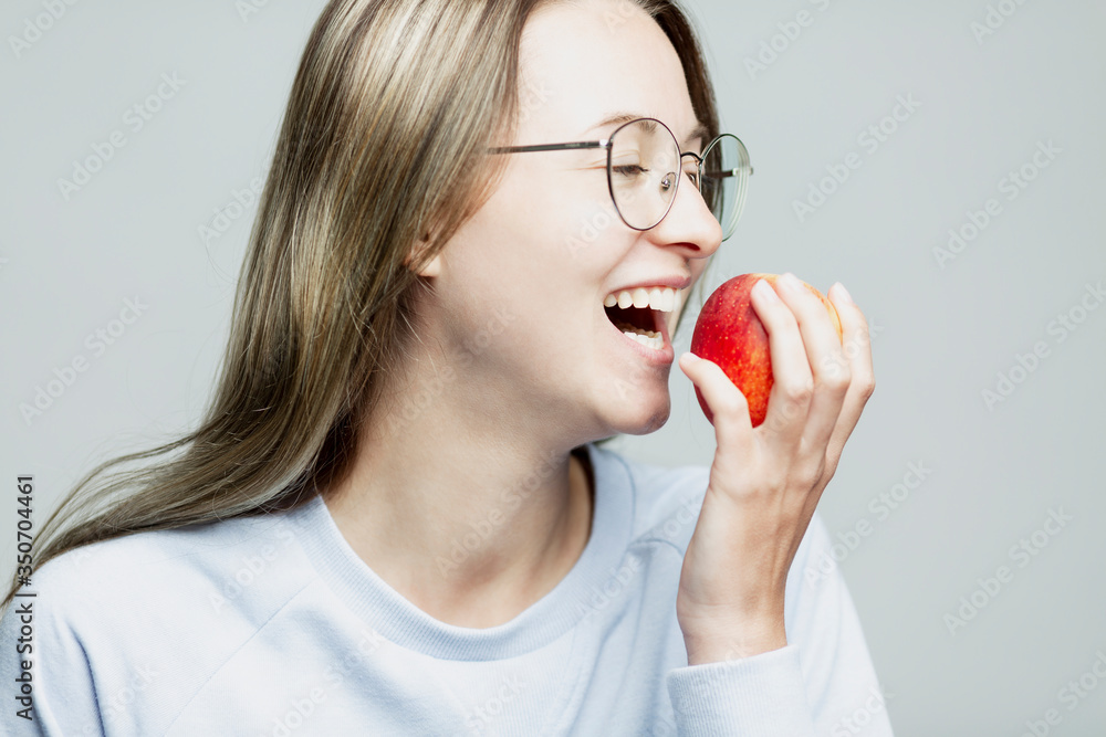 Laughing young girl eating an apple. Close-up. Healthy nutrition and vitamins. Laughing young girl eating an apple. Close-up. Healthy nutrition and vitamins.