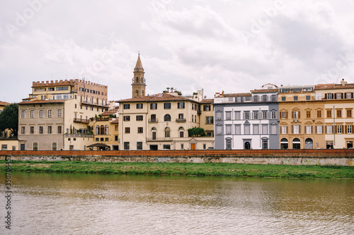 Houses on the waterfront in Florence, Italy, on the Arno River. The bell tower of basilica of Santo Spirito.