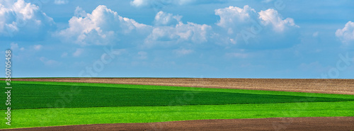 panorama of geometric lines of fields under sky with clouds and copy space