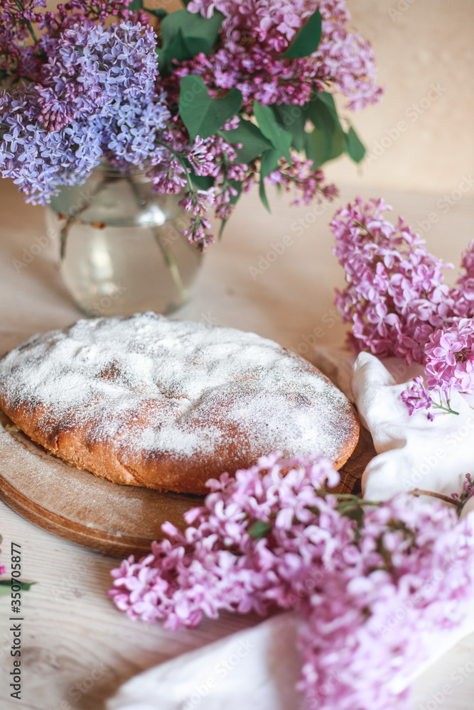 Homemade Apple pie on a wooden table next to a bowl of lilacs. Gentle toning. Homemade Apple pie on a wooden table next to a bowl of lilacs. Gentle toning.