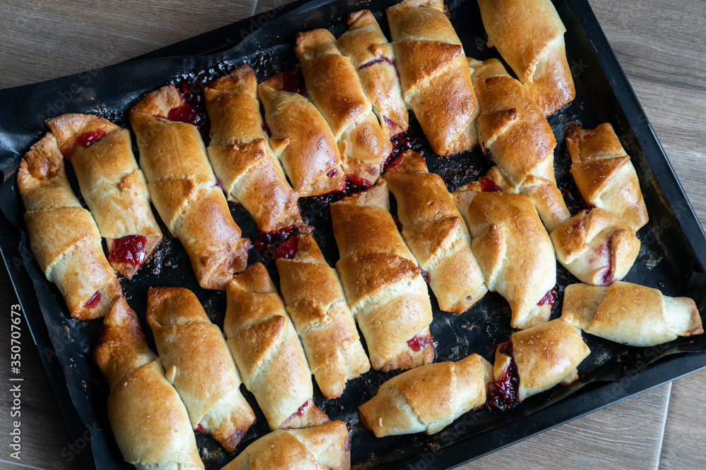 Pies with jam on a baking sheet. Cakes with jam on baking tray on wooden table. Homemade baking recipe. Tea time
