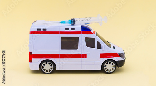 Toy ambulance carries a syringe on a yellow background