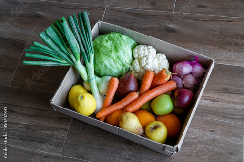 Obraz na płótnie Fresh vegetables in cardboard box on brown wood background. w salonie