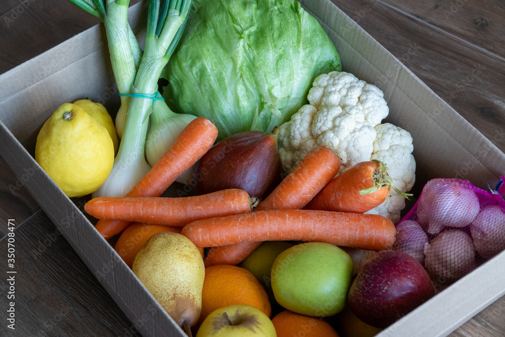 Fresh vegetables in cardboard box on brown wood background.