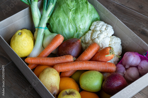 Obraz na płótnie Fresh vegetables in cardboard box on brown wood background. w salonie