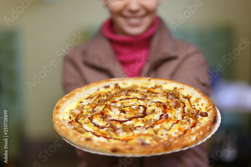 Fresh pizza in hands of beautiful young girl.