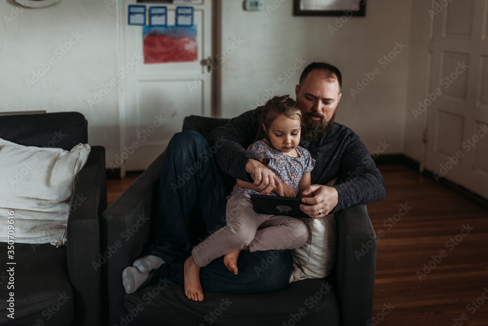 Dad and young daughter playing on tablet during isolation Dad and young daughter playing on tablet during isolation