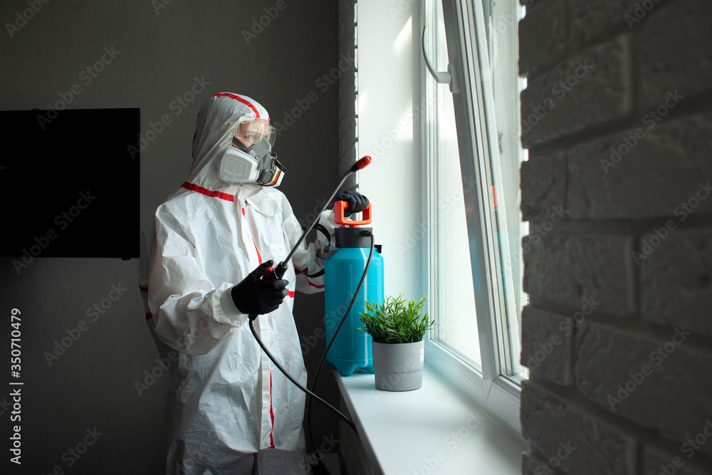pest control. A worker in a protective suit cleans the room from cockroaches with a spray gun, the sanitary service disinfects the apartment with a chemical agent