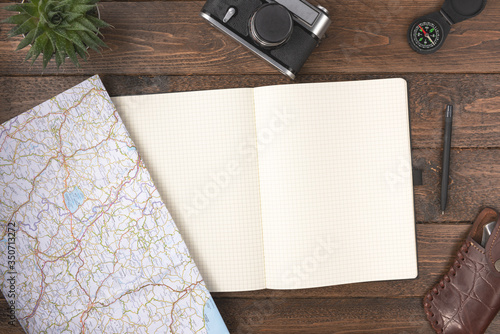 Travel planning concept. Traveler accessories. Old vintage camera with blank notepad and compass on wooden table background. Travel vacation concept. Flat lay, top view.