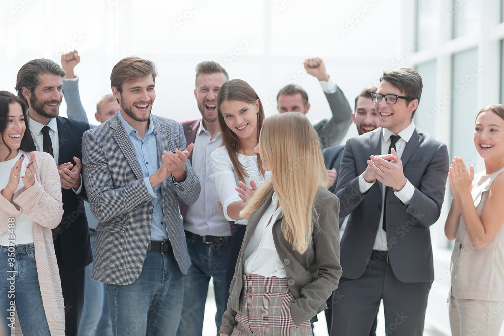 corporate group of employees applauding a young colleague