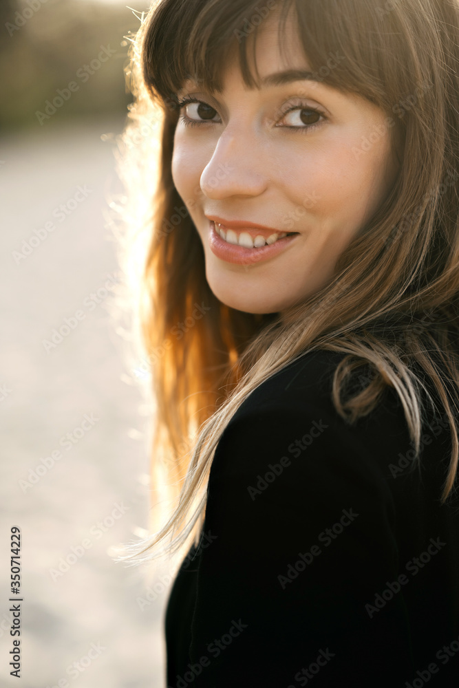 Happy young woman standing on sand on the beach at sunset. Youth, lifestyle and happiness concept. A photo with a blurred background. Happy young woman standing on sand on the beach at sunset. Youth, lifestyle and happiness concept. A photo with a blurred background.