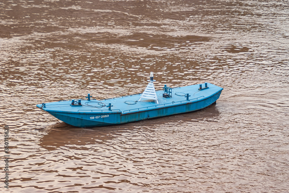 Chongqing, China - May 8, 2010: Evening light on Yangtze River. Closeup of blue buoy sloop on brown water with reflecting light. Chongqing, China - May 8, 2010: Evening light on Yangtze River. Closeup of blue buoy sloop on brown water with reflecting light.
