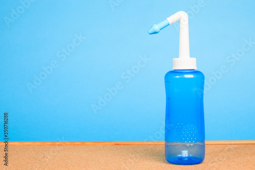 blue water pulse nasal wash bottle on a wooden table, nasal irrigation concept