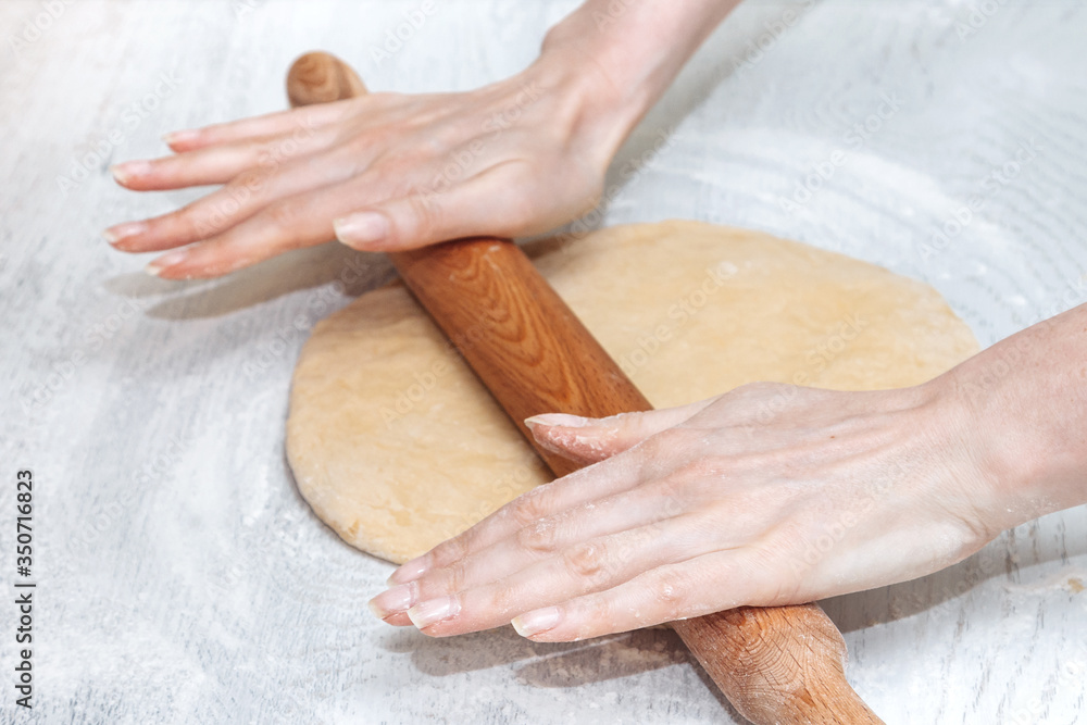 girl rolls out raw dough in the kitchen. the concept of home cooking. making homemade dough girl rolls out raw dough in the kitchen. the concept of home cooking. making homemade dough