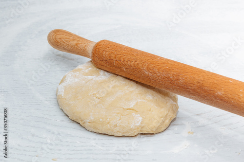 dough and rolling pin on the white kitchen table. the concept of home cooking. cooking homemade dough. close up