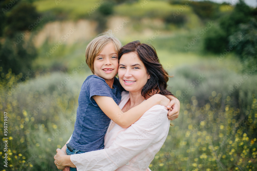 Portrait of Mother and Son Missing His Front Teeth Hugging in a Field of Flowers Portrait of Mother and Son Missing His Front Teeth Hugging in a Field of Flowers