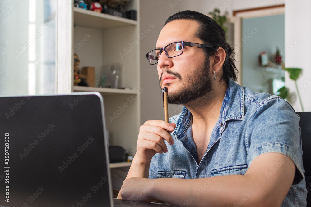 pensive young man telecommuting in front of the laptop pensive young man telecommuting in front of the laptop
