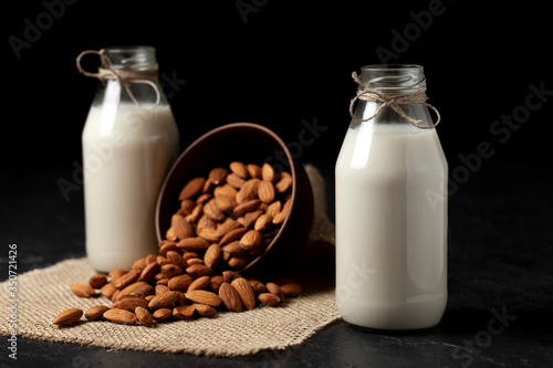 almond milk in bottles with nuts on a black table, a variety of dairy products without sugar and lactose, a vegetarian drink