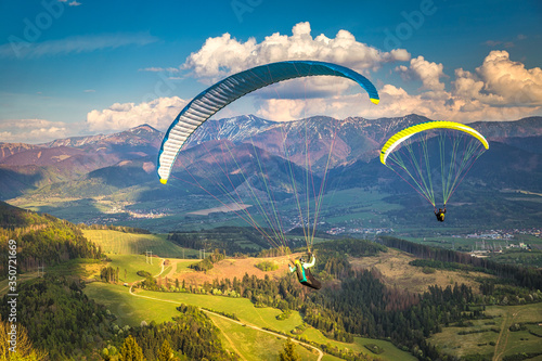 Flying paragliders from the Stranik hill over the mountainous landscape of the Zilina basin in the north of Slovakia..Mala Fatra National Park in the background, Slovakia, Europe. photo