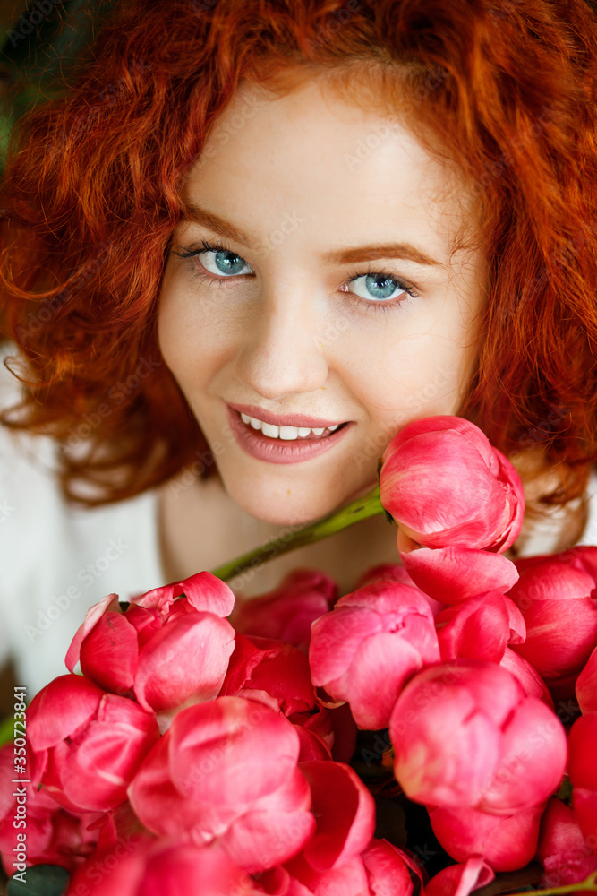 Sweet red-haired girl holding a bouquet of pink peonies Sweet red-haired girl holding a bouquet of pink peonies