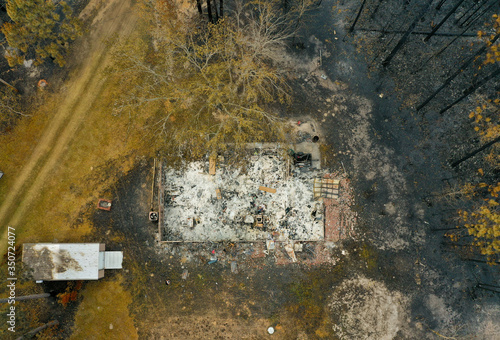 Forest wildfire in the forest with some burned trees and houses. Ashes from wood and houses