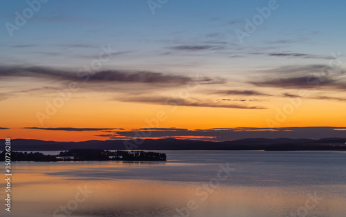 Bright clouds over a city pond with a promenade and a small island