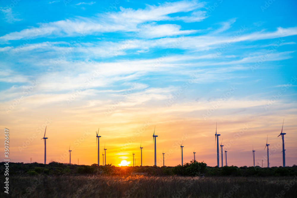 WIND POWER GENERATORS ONSHORE SILHOUETTES WITH SUNSET