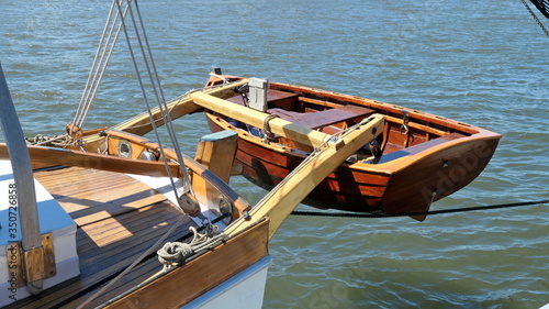 Dinghy, small rowing boat, made of mahogany wood, attached to the stern of a vintage sailing yacht © anela47