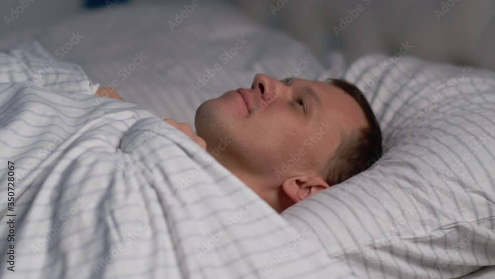 A man brings to bed a head on a pillow covered with a blanket and falls asleep A man brings to bed a head on a pillow covered with a blanket and falls asleep