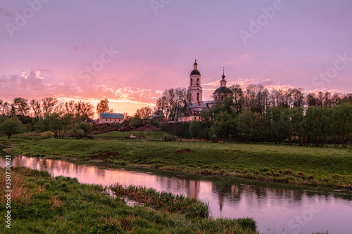 Fototapeta Naklejka Na Ścianę i Meble -  Orthodox Church by the river in the evening sunset