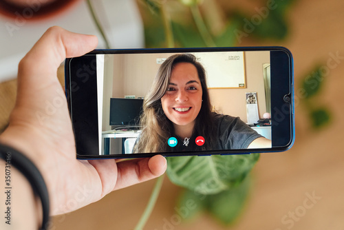 Photos Closeup of a female hand holding a smart phone during a skype video call with he